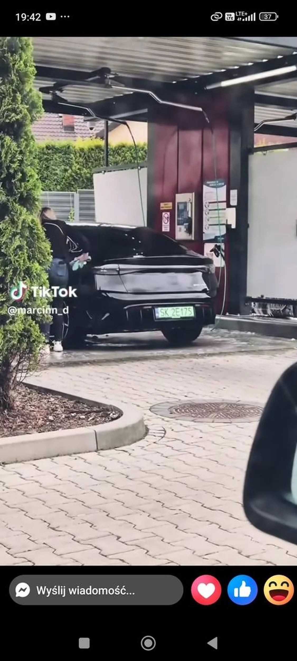 Baran wyciera auto podczas gdy ludzie czekają w kolejce do myjni.