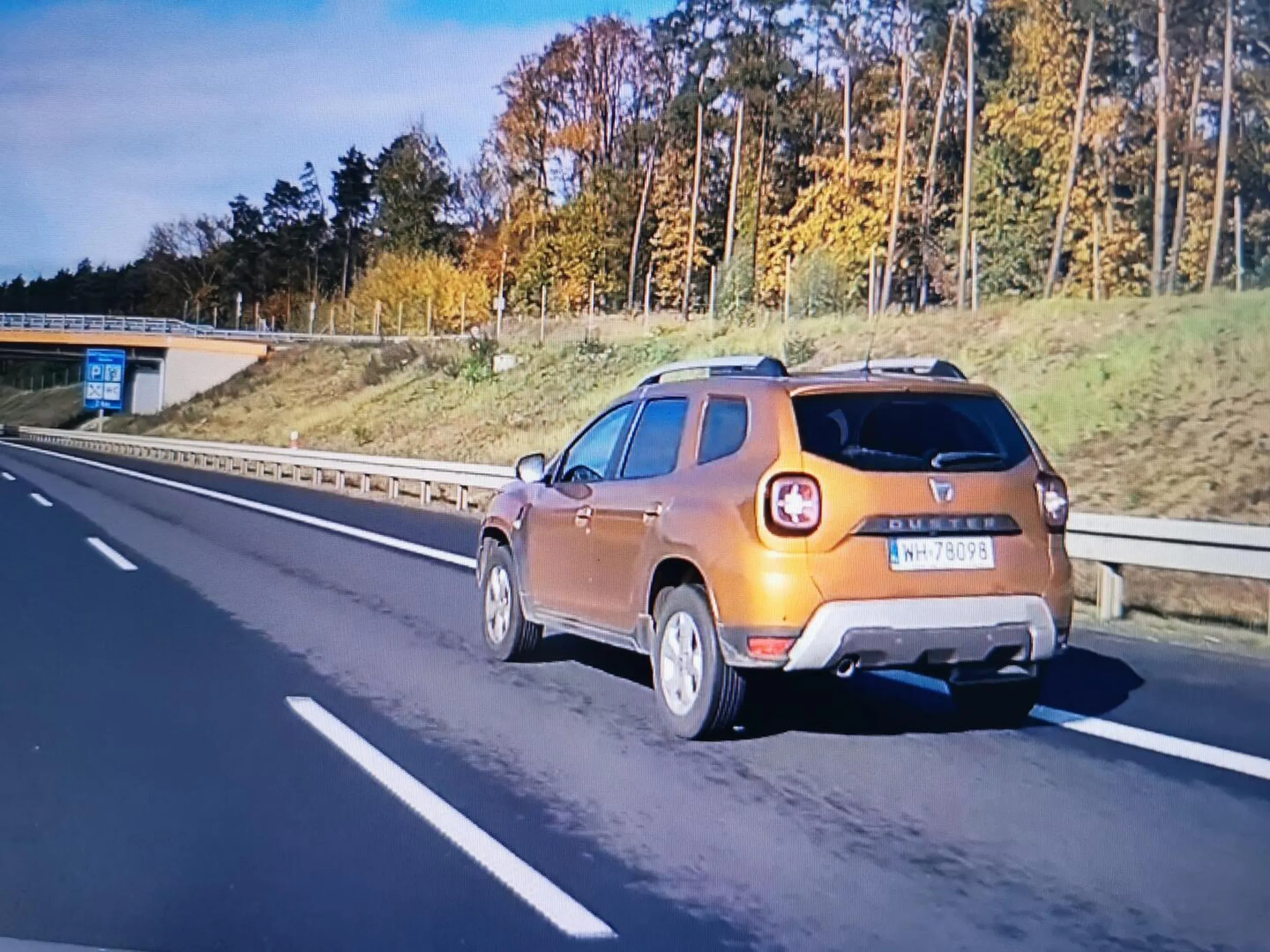 Dacia koloru brązu... Kierujący ma duże problemy z utrzymaniem się na swoim pasie. Jedną ręka na kierownicy u góry i lata od pobocza do pobocza.