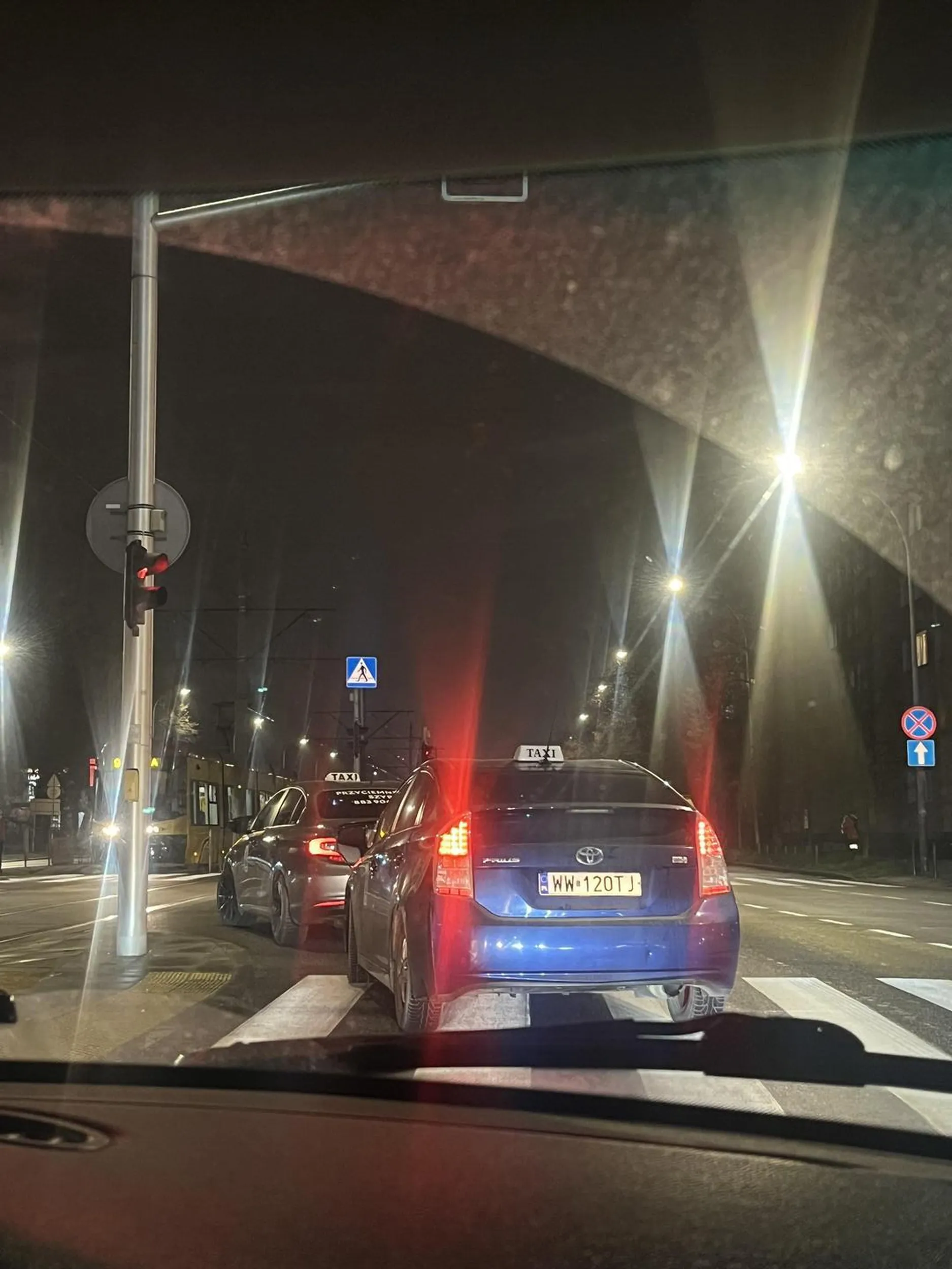 Taksiarz zmienia pas z prawego na lewy na czerwonym świetle i przez przejście dla pieszych wbijając się przed normalnie stojące na skrzyżowaniu samochody. No nie powiem, żeby taki manewr zrobić to  trzeba być kimś specjalnym