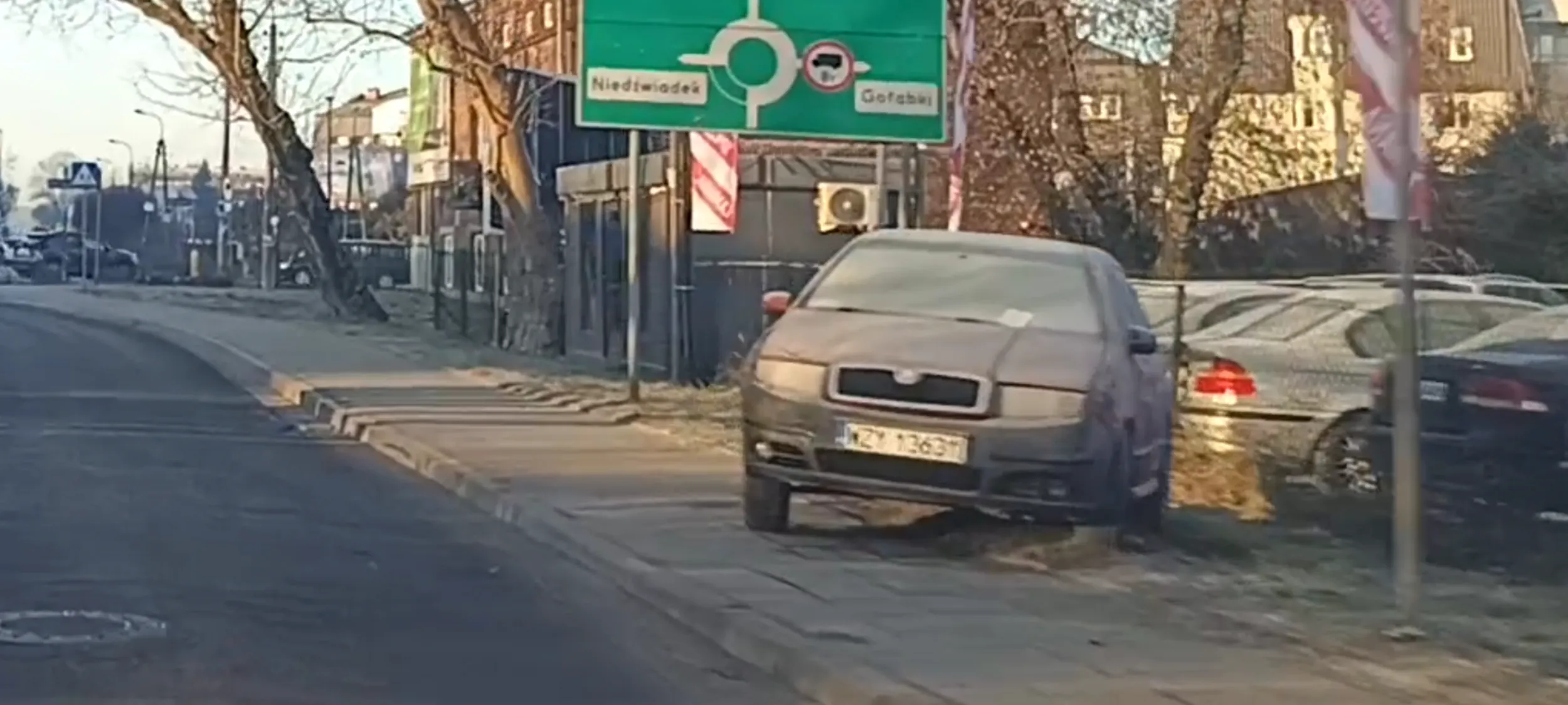 Patologia zaparkowała wraka w rdzy na trawniku i chodniku.