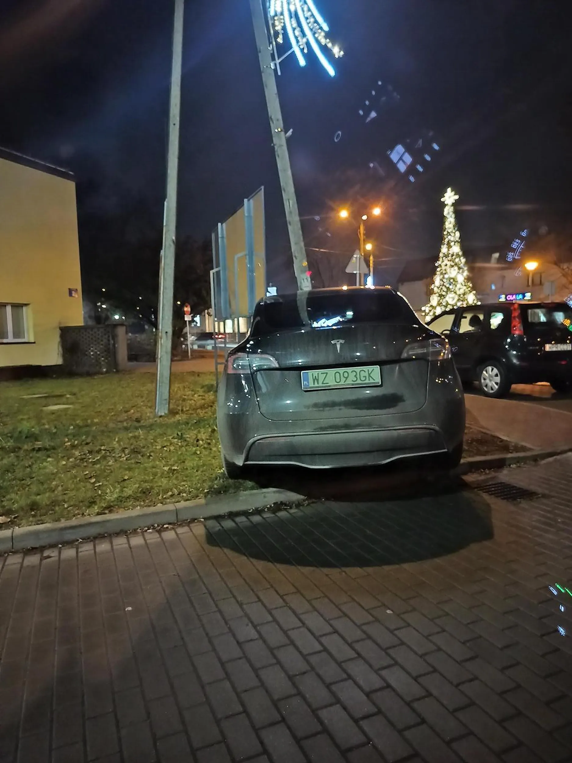 Bieda za wsi parkuje wraka na trawniku pod liceum w Piastowie.