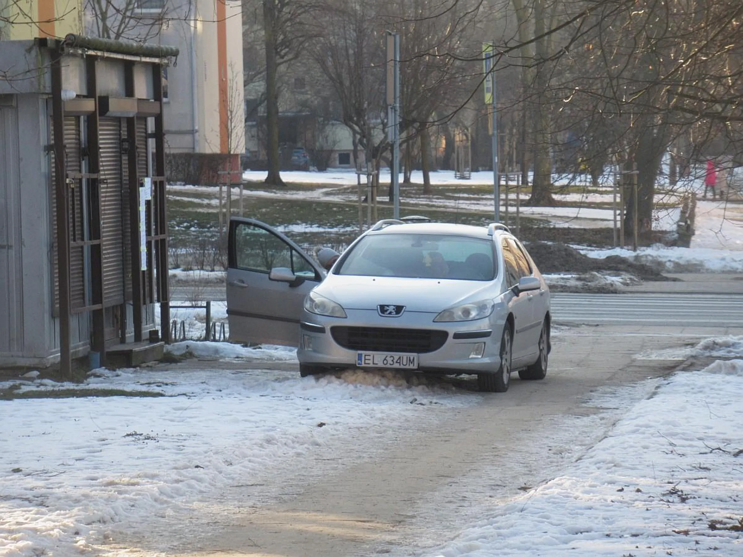 Handlarz podjeżdża pod swój sklep jadąc wzdłuż po przejściu dla pieszych i chodniku.