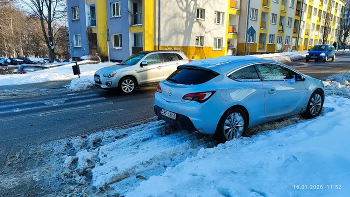 Kierowca parkuje pojazd bezpośrednio za przejściem na drodze dwukierunkowej.