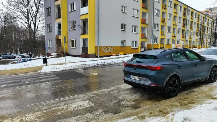 Kierowca parkuje pojazd bezpośrednio za przejściem na drodze dwukierunkowej.