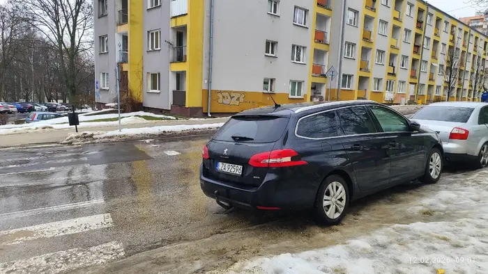 Kierowca parkuje pojazd bezpośrednio za przejściem na drodze dwukierunkowej.