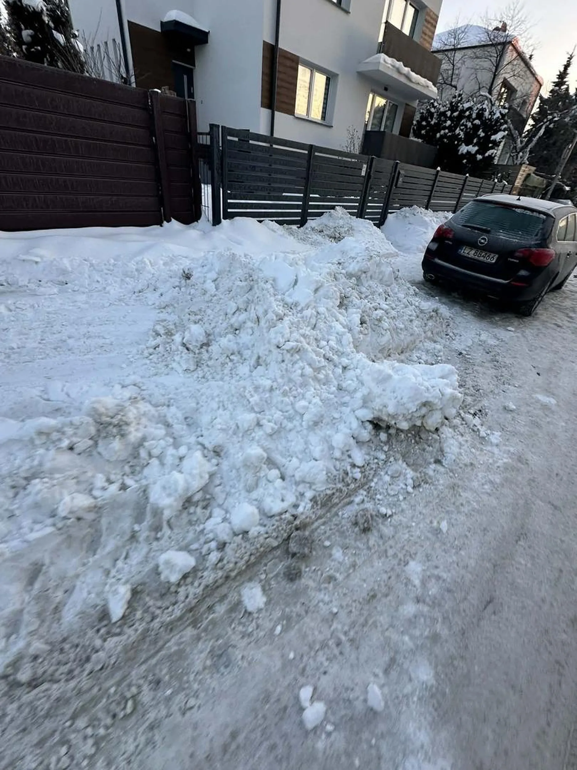 Samochód stoi na ulicy, a do tego nie odśnieżony chodnik koło samolotu