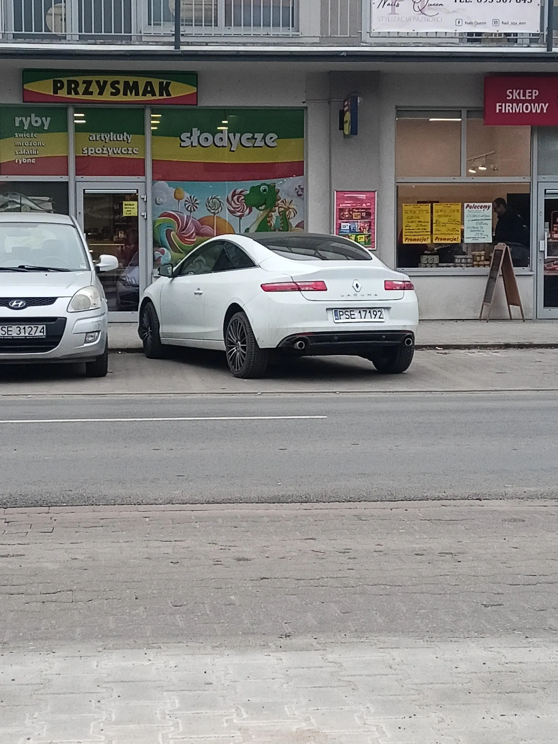 Jakąś babka stoi krzywo, zajmuje dwa miejsca na parkingu przed sklepami obok szkoły
