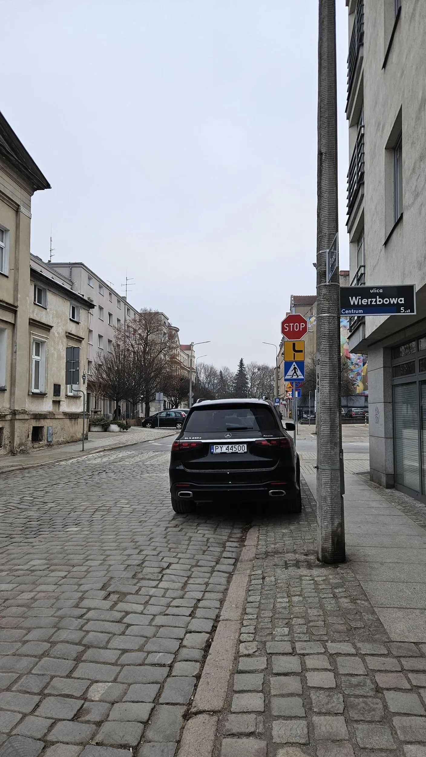 Stoi na zakazie postoju na chodniku tuż przed przejściem dla pieszych ograniczając ich widoczność.