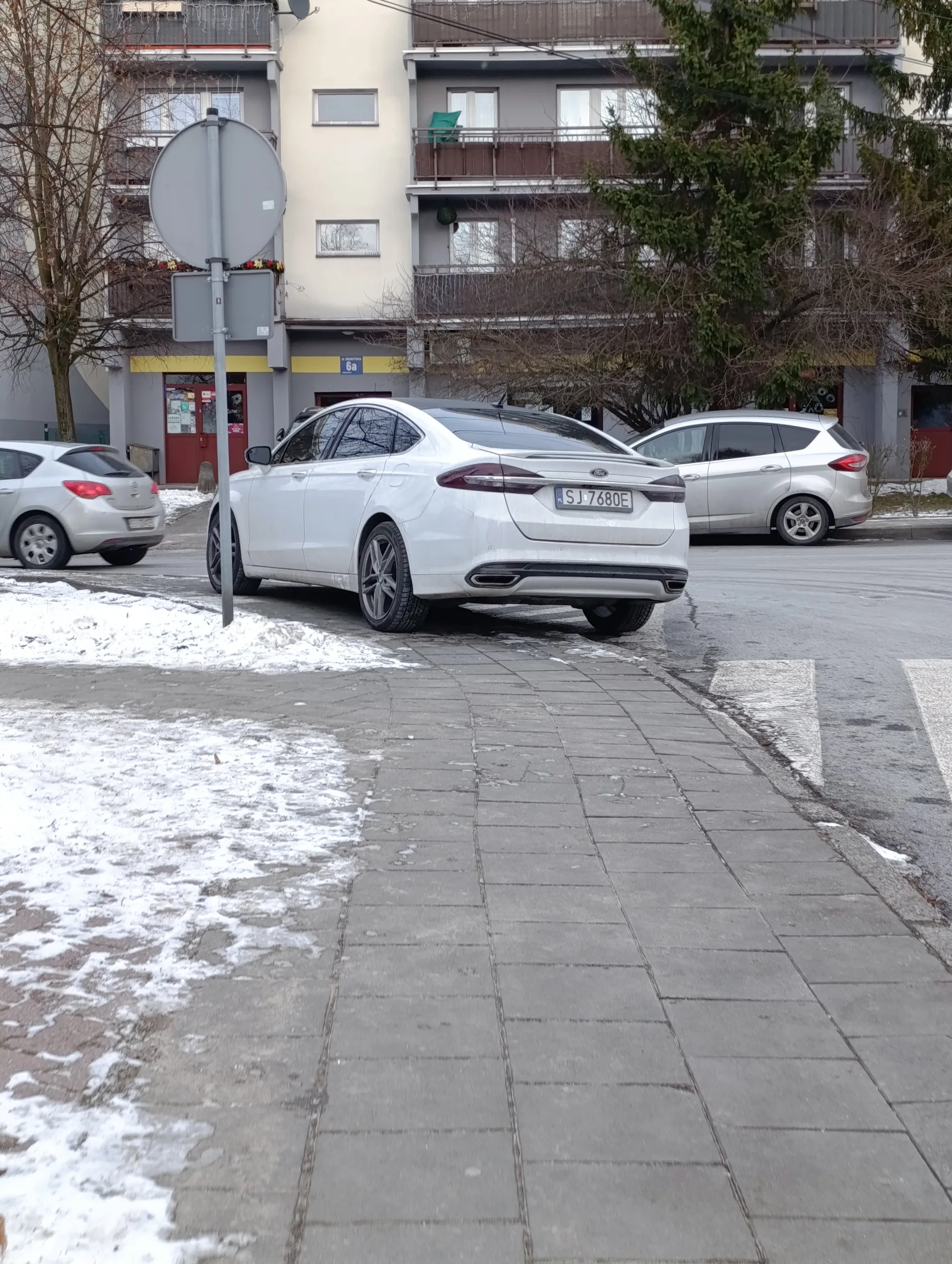 Kierowca ford parkuje na polu wyłączanym z ruchu i chodniku
