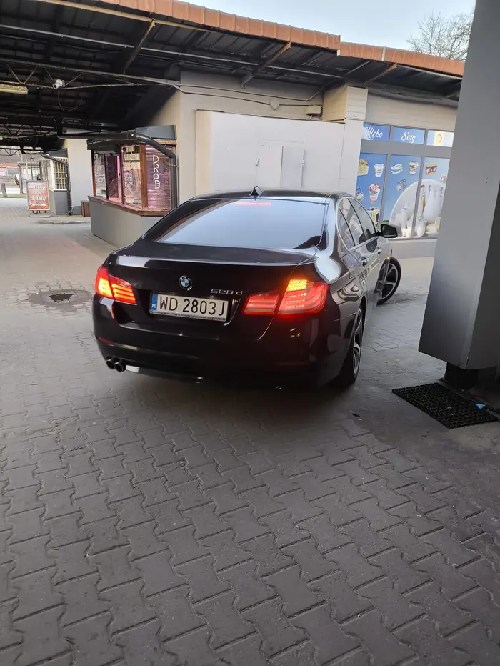 Kierowca w BMW przeciskający się między budkami na bazarku. Jazda po chodniku i przeganianie pieszych to dla niego norma.