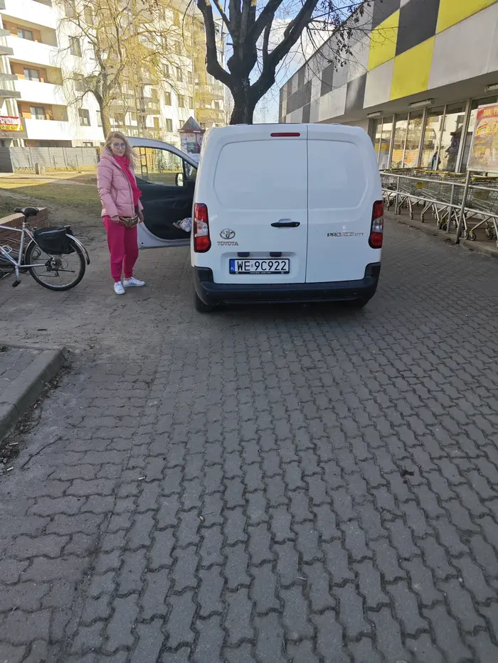 Tym autem jeździ bardzo agresywna kobieta, która chyba w ogóle nie posiada prawa jazdy. Wydarła się na mnie pod sklepem Biedronka, gdzie akurat robiłam zdjęcie dla innego auta zastawiającego przejście dla pieszych i wyjście ewakuacyjne. Okazało się, że babsko stoi obok, też łamiąc przepisy. Nie planowałam robić jej zdjęcia, ale w tej sytuacji musiałam. Kobieta próbowała odebrać mi mój telefon i krzyczała, że nie mam prawa robić zdjęć autom (co jest bzdurą), a ona jako dostawca może parkować, gdzie chce. Chcąc uniknąć fotki wsiadła do auta i ruszyła agresywnie na mnie, jej auto otarło się o mnie (ja stałam nieruchomo na przejściu dla pieszych), aż złożyło się lusterko. Następnie przez te same przejście wjechała na chodnik pod sklepem. Osoba absolutnie chora i niezrównoważona.