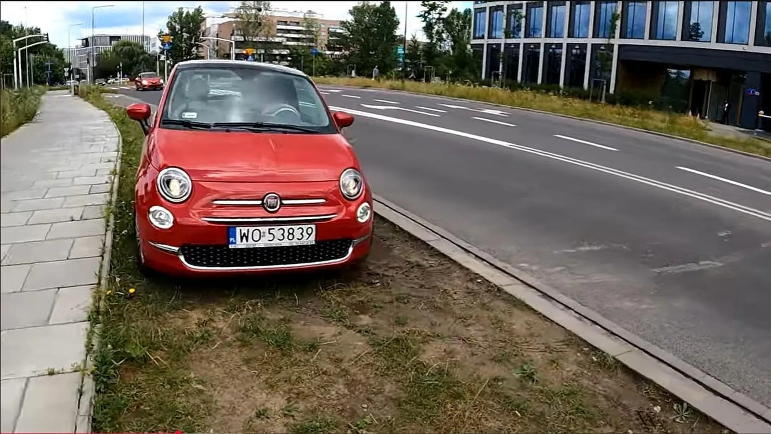 Mężczyzna przebrany za kobietę parkuje na trawniku.
