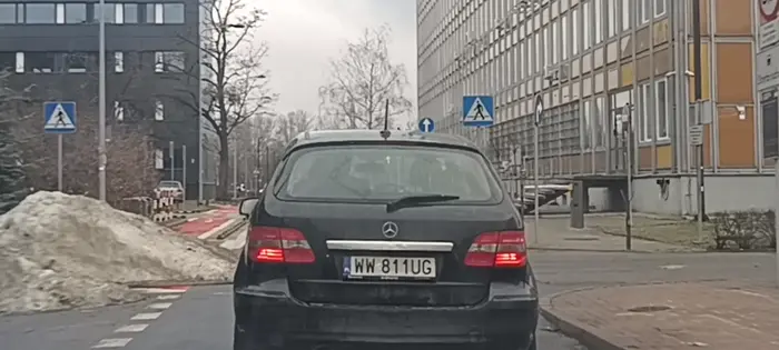 Bandyta drogowy skręca w lewo w ulicę pomimo znaku nakazu jazdy prosto i mógł doprowadzić do wypadku.