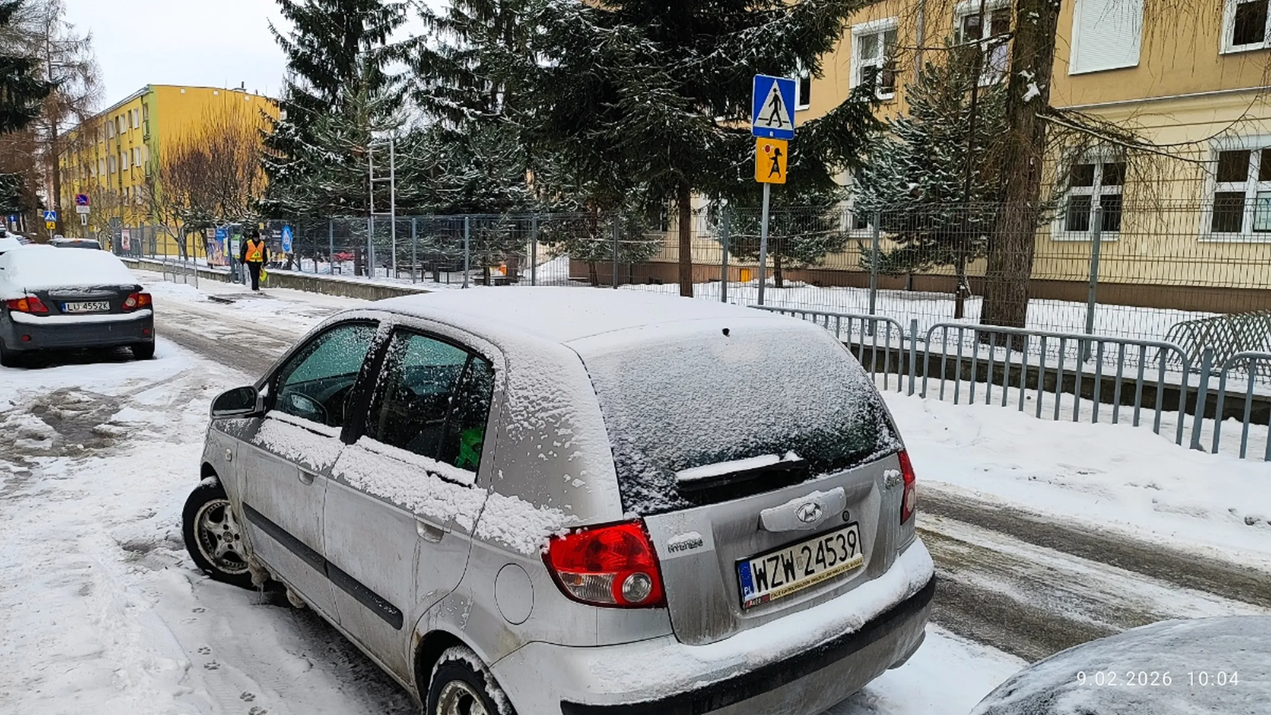 Kierowca parkuje pojazd bezpośrednio przed przejściem dla pieszych w pobliżu szkoły podstawowej.