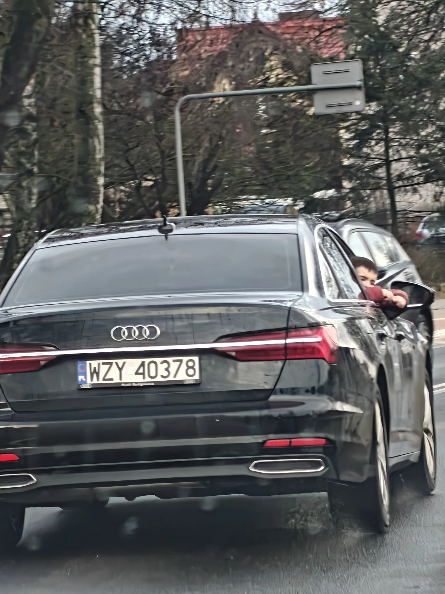 Dziecko niebezpiecznie wychylające się z samochodu podczas jazdy, prawdopodobnie bez pasów. (Kiedy samochód stanął na światłach, dziecko wychylało się bardziej z samochodu. Gdyby ktoś wszedł temu komuś pod samochód, i musiałby mocno zahamować, to nie skończyłoby się to bynajmniej dobrze dla dziecka w samochodzie)